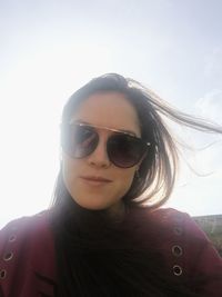 Portrait of young woman wearing sunglasses against sky