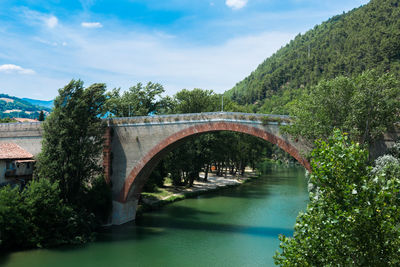 Arch bridge over river against sky