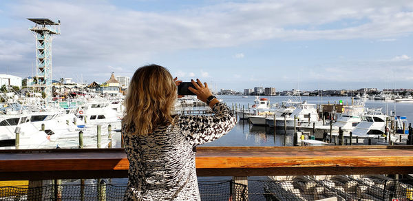 Woman photographing harbor in city