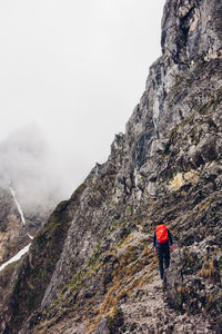 Rear view of hiker with backpack walking on cliff during foggy weather