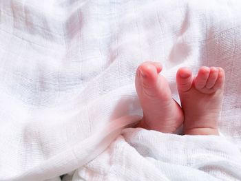 Low section of baby feet on bed