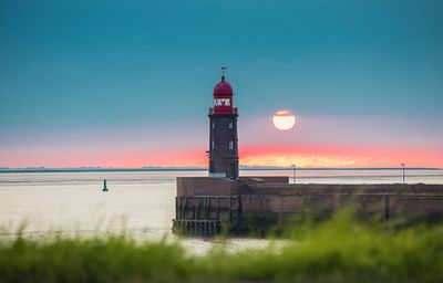 Lighthouse by sea against sky