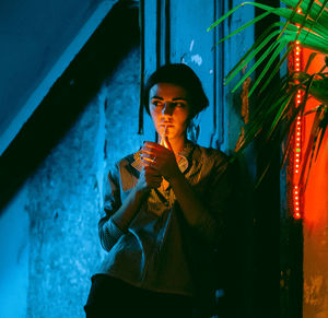 Portrait of young woman standing against wall