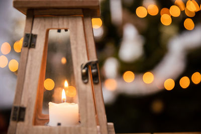 A candle burns closed inside a decorative lantern on christmas day.