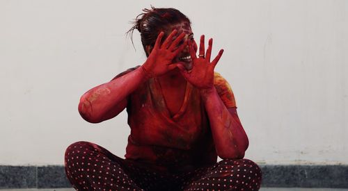 Close-up of woman covered with powder paint while sitting against wall