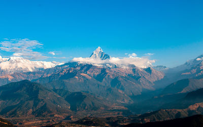 Scenic view of snowcapped mountains against blue sky