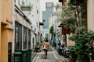 Rear view of man walking on alley in city