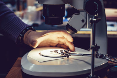 Cropped image of technician adjusting microscope slide indoors