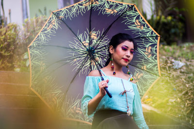 Young woman holding umbrella in city