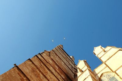 Low angle view of bird flying against clear blue sky