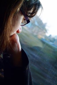 Close-up of young woman looking through glass window