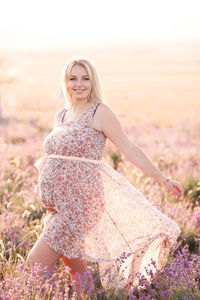 Happy pregnant woman standing on field