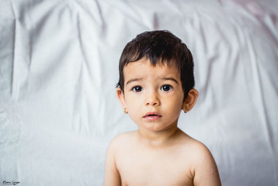 Portrait of shirtless boy lying on bed