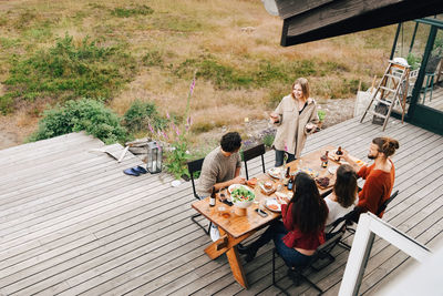 High angle view of woman talking with friends while enjoying dinner in patio