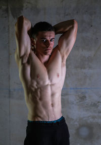 Portrait of shirtless man standing against wall