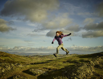 Full length of person jumping on landscape against sky