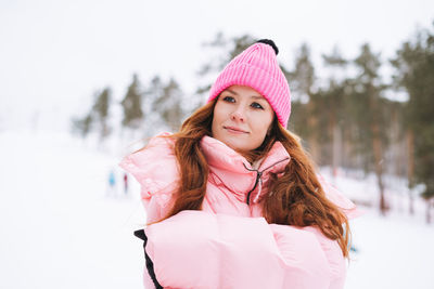 Portrait of smiling young woman standing against snow