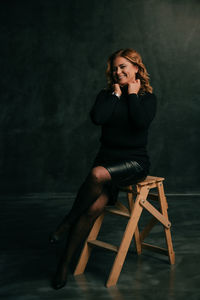 Full length of young woman sitting on chair