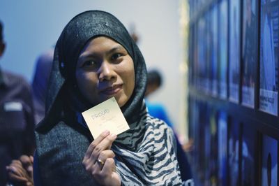 Portrait of woman wearing hijab holding paper