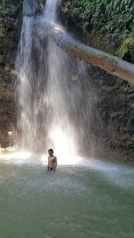 High angle view of teenage boy standing by waterfall