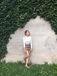 Portrait of young woman standing against plants