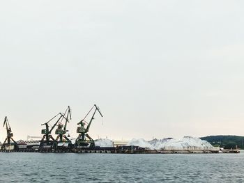 Commercial dock by sea against clear sky