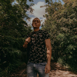 Portrait of young man standing against trees