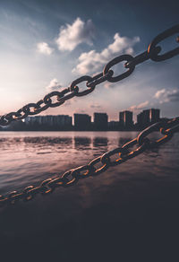 Close-up of chain on rope against sky during sunset