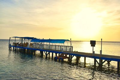 Pier on sea against sky during sunset