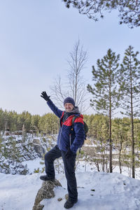 Senior man posing on snowy cliff above scenic frozen talc stone lake in winter, russia