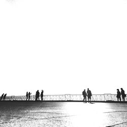 People walking on beach against clear sky
