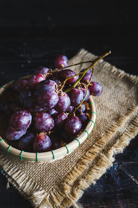 High angle view of red grapes in bowl on wicker mat