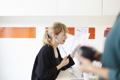 Mid adult businesswoman holding document while reading document in office