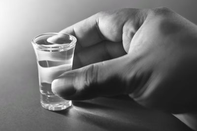 Close-up of hand holding drink on table