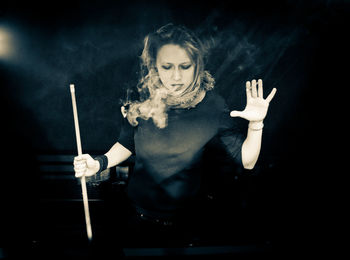 Woman smoking cigarette against black background