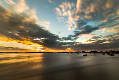 Scenic view of sea against cloudy sky at sunset