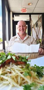 Portrait of man by basket and food on table