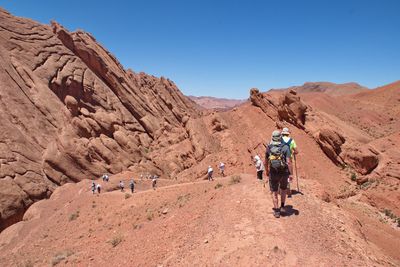 People hiking on mountain against clear sky