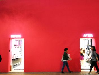 Full length of woman standing against red wall