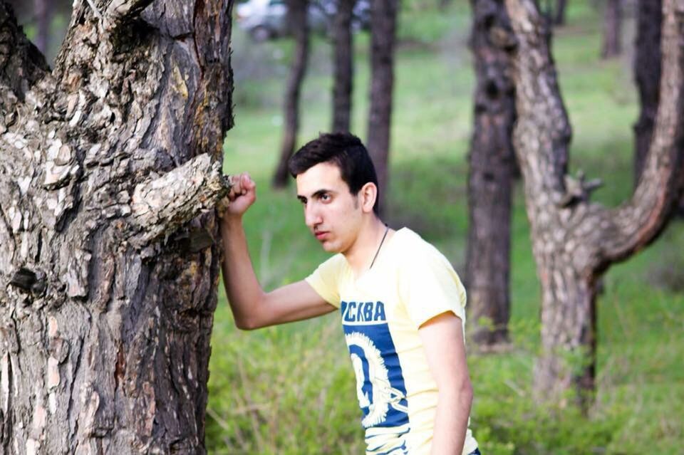 tree, person, lifestyles, leisure activity, focus on foreground, forest, tree trunk, looking at camera, portrait, front view, happiness, casual clothing, smiling, childhood, holding, boys, elementary age, waist up