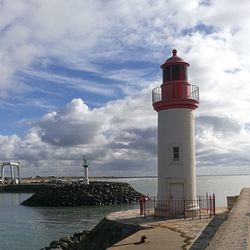 Lighthouse by sea against sky