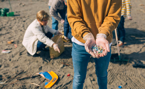 Midsection of woman holding wastes at beach