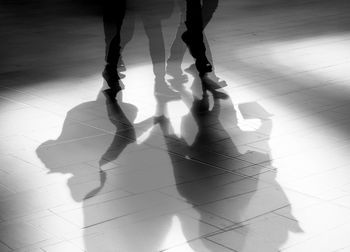 Low section of woman with shadow on tiled floor