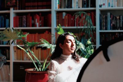 Portrait of young woman looking at potted plant