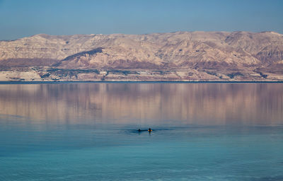 Scenic view of sea by mountains against sky