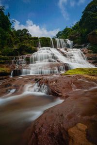 Scenic view of waterfall against sky