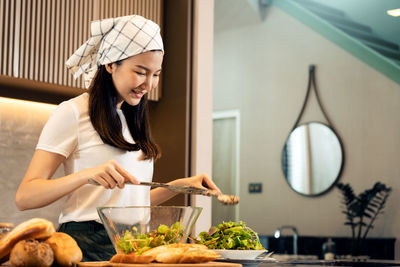 Side view of young woman preparing food at home