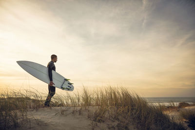 Man on beach against sky during sunset