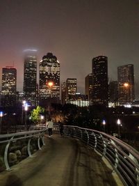 Illuminated street amidst buildings in city at night