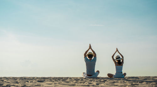 People relaxing on beach against sky